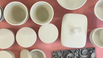 White ceramic containers on a pink surface.
