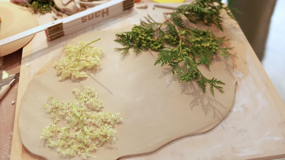 Flowers and leaves on clay slab, wooden board.