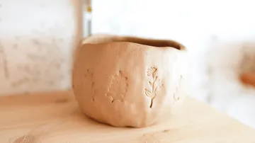 Handgemachter Tontopf auf Holzoberfläche.