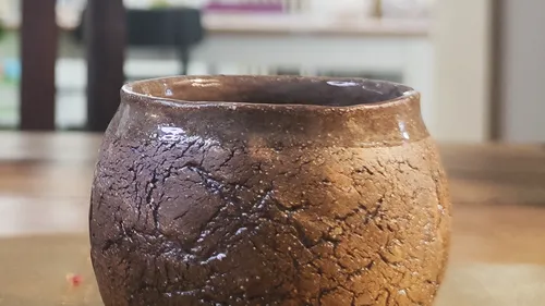 Brown ceramic cup on wooden table.