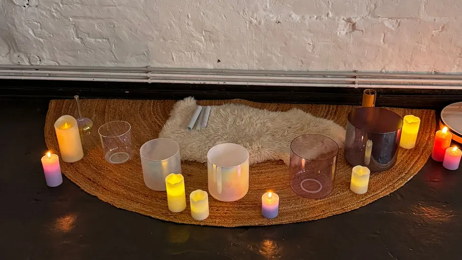 Singing bowls and candles on a rug.