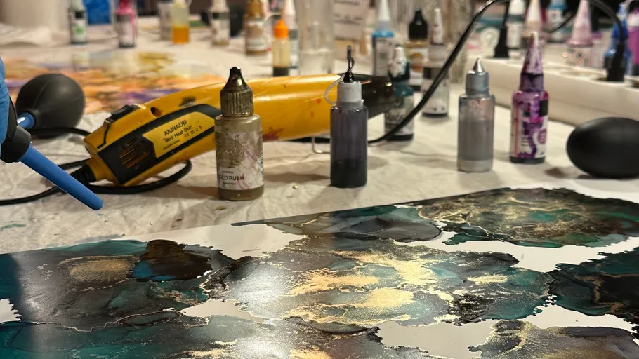 Kunstmaterialien auf Tisch mit abstraktem Gemälde.