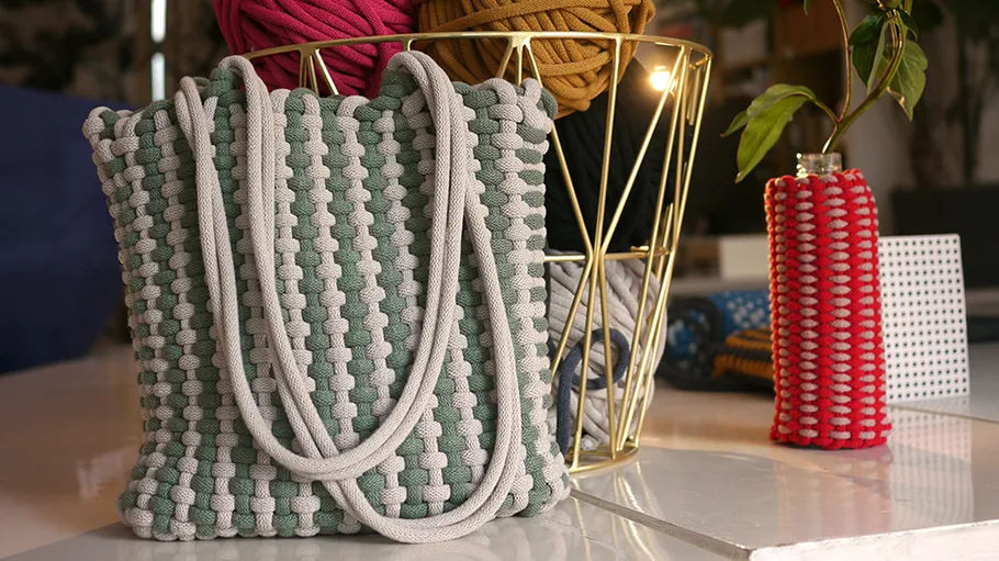 Geflochtene Tasche auf Tisch, Garn und Vase daneben.