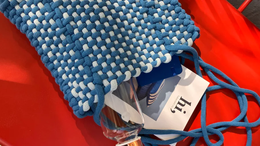 Knitted blue-white bag holding a water bottle.