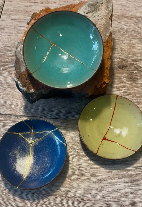 Drei Kintsugi-Schalen auf Holzoberfläche.