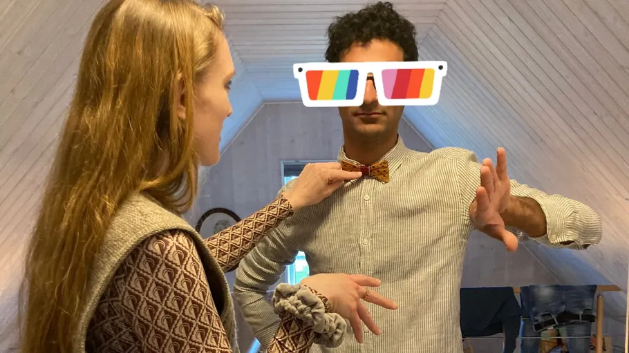 Woman adjusting man's bow tie in attic.