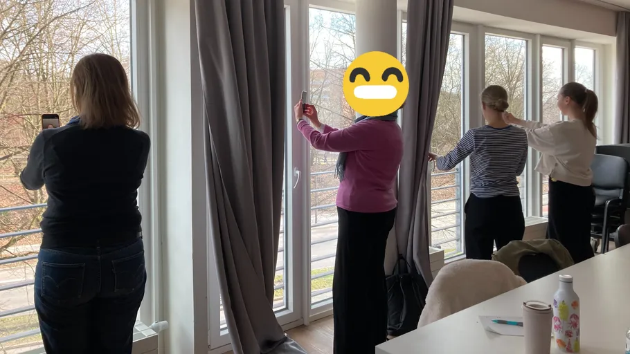 Four people photographing scenery outside large windows.
