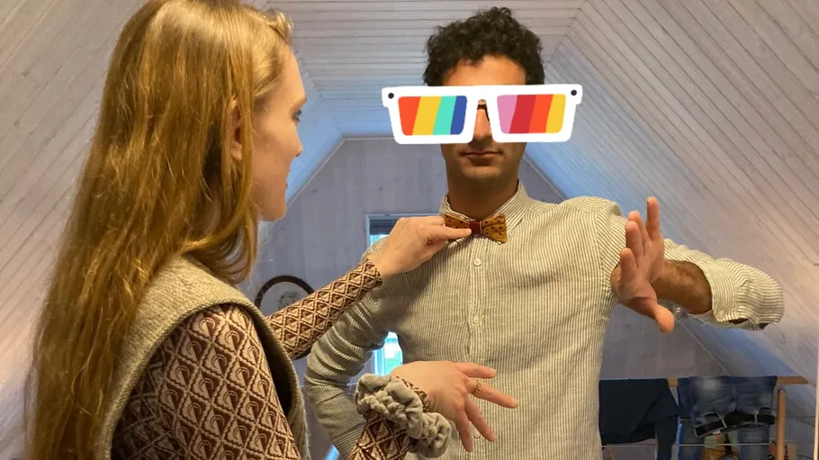 Woman adjusts man's bow tie indoors.