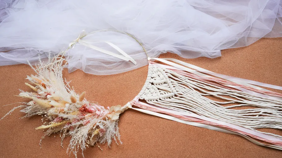 Floral macrame hoop with tulle on corkboard.