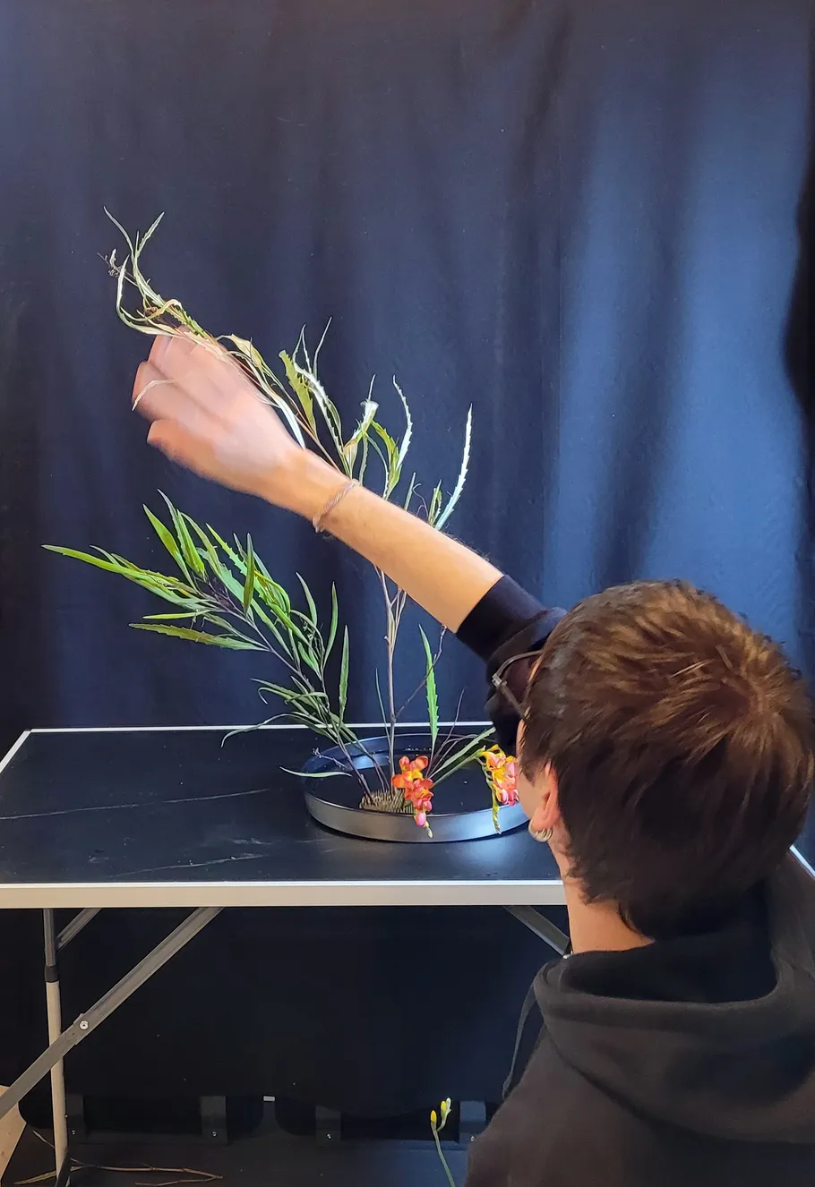 Person arrangiert Blumen auf schwarzem Tisch.