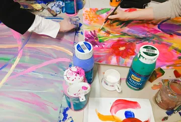 People painting on canvas with bright colors.
