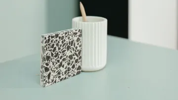 Fliesenmuster mit Terrazzo-Muster neben weißem Becher.