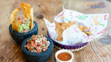 Guacamole und Salsa mit Tortillachips auf Tisch.