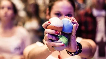 Person holding three colorful juggling balls.