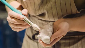 Person painting ceramic sculpture indoors.