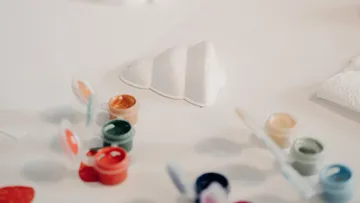 Paint pots and white sculpture on table.