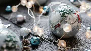 Christmas ornaments and lights on a gray surface.