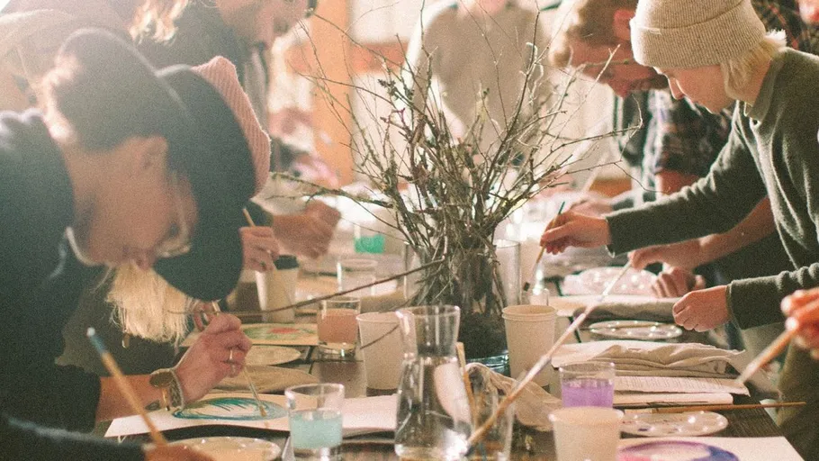 People painting around a table, indoor setting.