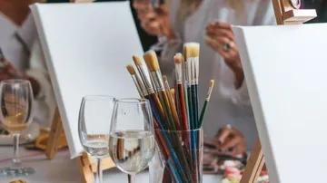 Pinsel und Gläser auf einem Tisch, Menschen malen.