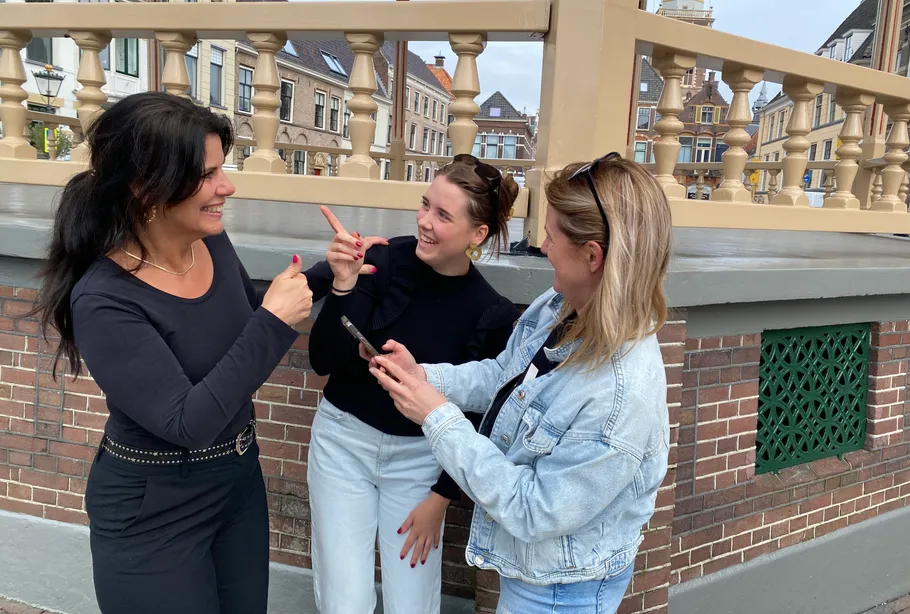 Three women chatting happily on a bridge.