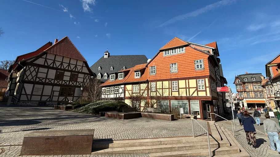 Half-timbered houses under blue sky in town square.