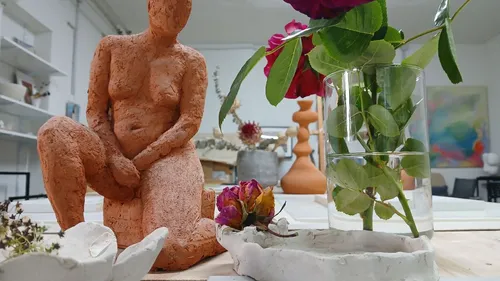 Terracotta sculpture and flowers on a table.