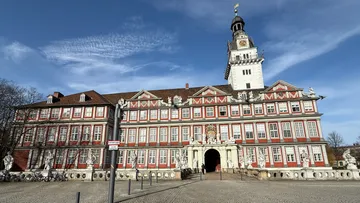 Prunkvolles Gebäude mit Uhrturm unter blauem Himmel.