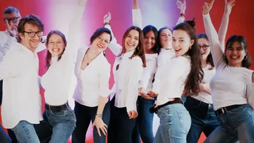 Group of people posing, smiling in casual outfits.