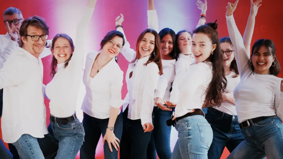 Group of people smiling, wearing white tops.