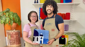 Zwei Personen halten bunte Textilkunst drinnen.