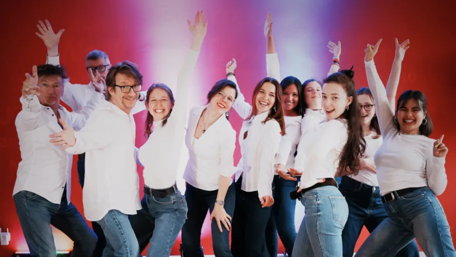 Group posing energetically against a red background.