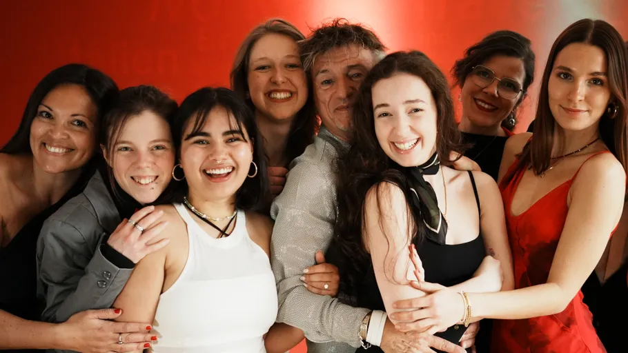 Group of eight smiling people in formal attire.