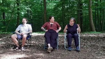 Drei Personen sitzen im Wald im Freien.