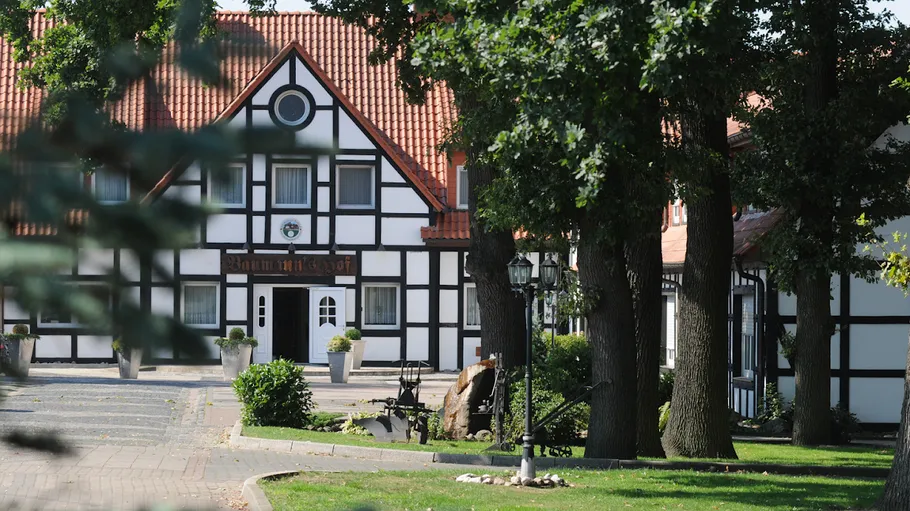 Traditionelles Gebäude mit rotem Dach, von Bäumen umgeben.