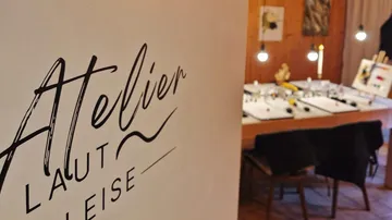 Schild mit 'Atelier Laut Leise' und Kunsttisch.