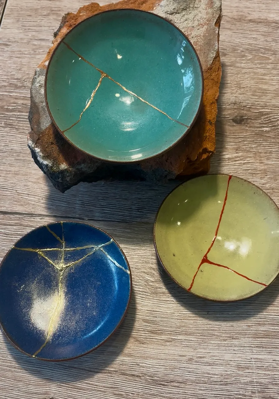 Drei Kintsugi-Schalen auf Holzoberfläche.