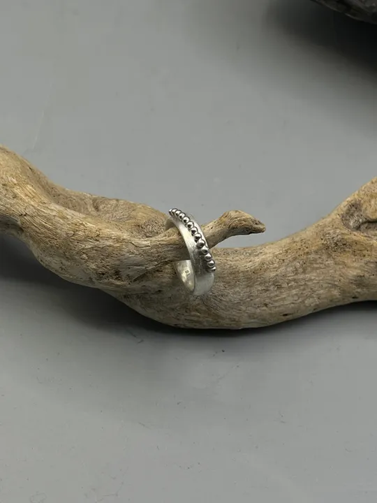 Silberring auf einem verdrehten Holzast.