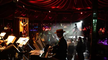 Musiker spielt in schummrigem Cabaret-Umfeld.
