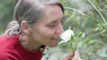 Woman smelling a white flower in nature.