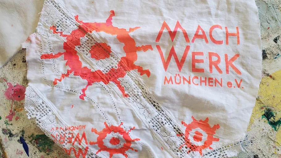 Fabric with red designs and lace, text visible.