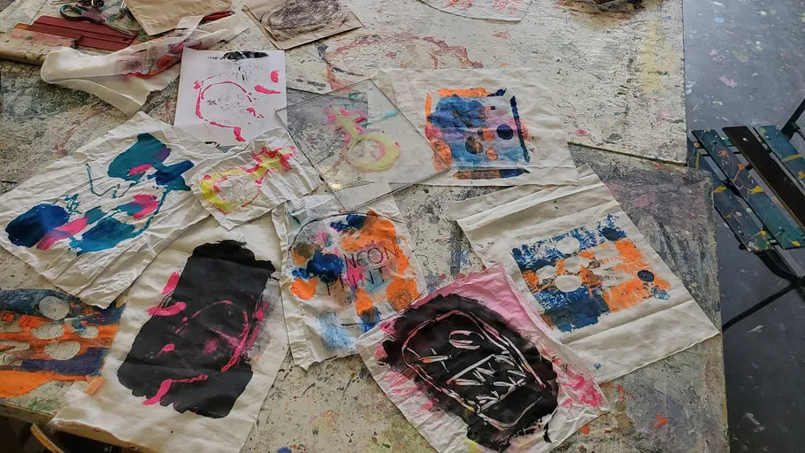 Colorful artworks scattered on a paint-splattered table.