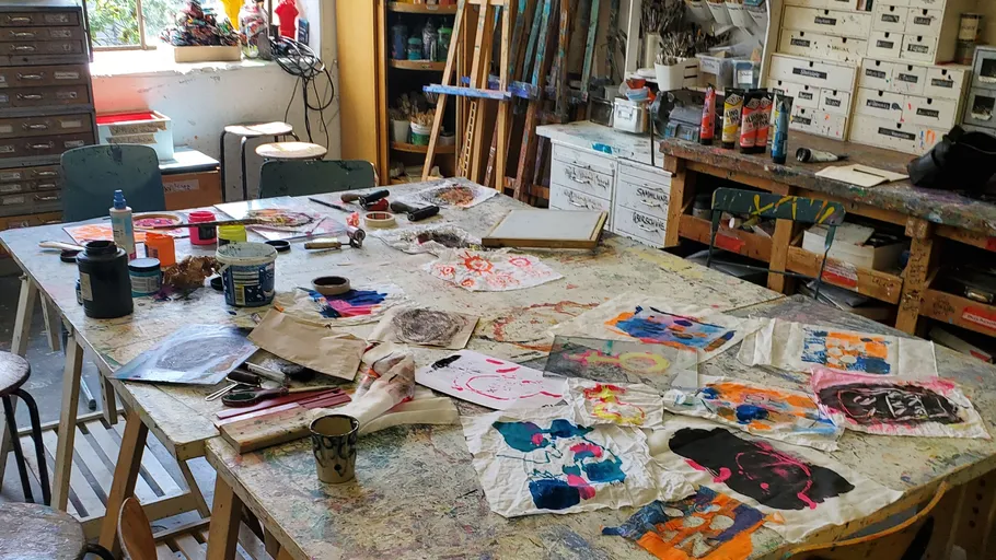 Art studio with colorful paintings on tables.
