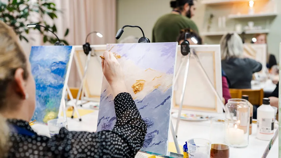 Person painting on canvas in art class.