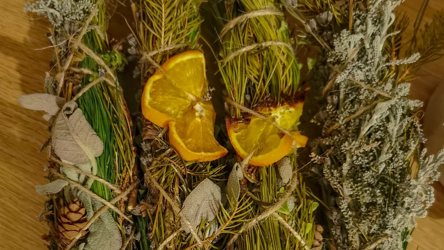 Herb bundles with orange slices on wood.