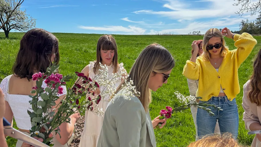 Women arranging flowers in a sunny field.