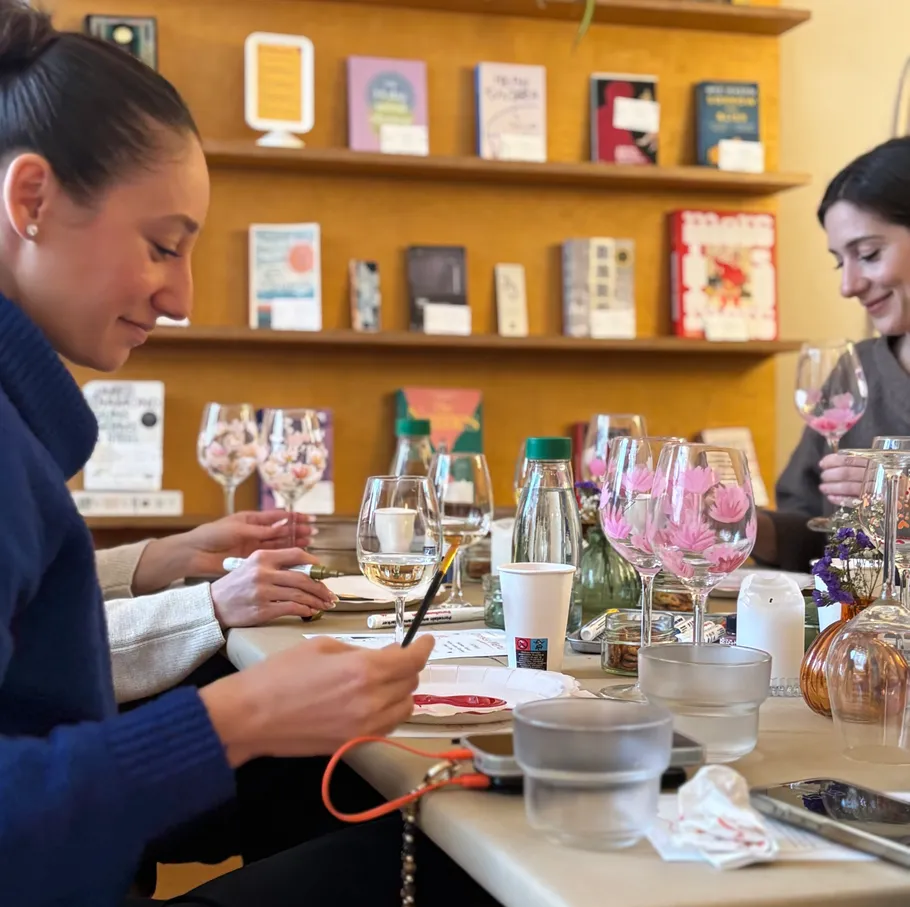 Women painting wine glasses at a table.