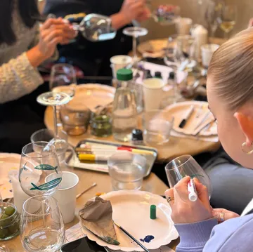Personen bemalen Weingläser an einem Tisch.