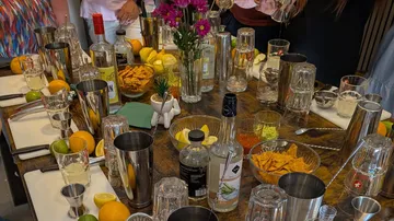 Cocktailbedarf auf Tisch, Leute gesellig drumherum.