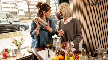 Zwei Frauen bereiten Getränke in gemütlichem Café zu.