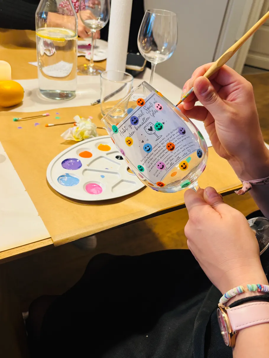 Person painting glass with colorful faces.